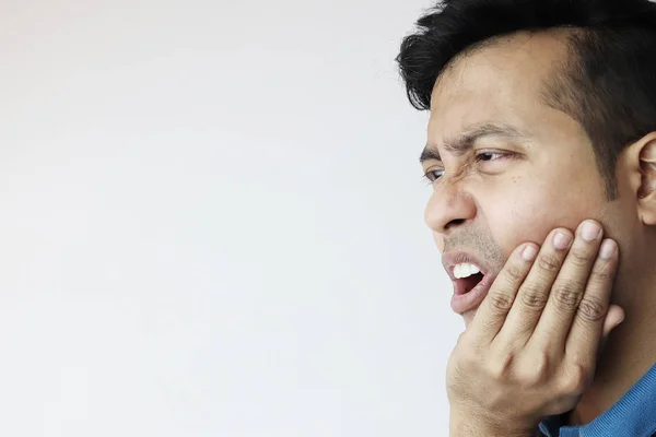 Um jovem macho segurando o queixo inferior em dor e agonia devido à dor de dente isolado em branco com espaço de cópia para texto . — Fotografia de Stock