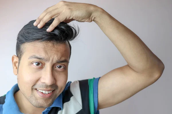 Un joven indio de estilo masculino es el pelo con las manos y una expresión positiva en la cara aislada en gris con espacio de copia para el texto . — Foto de Stock