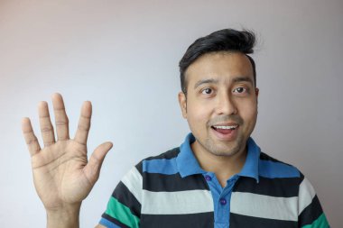 Kendine güvenen ve gülümseyen genç bir Hintli adam beyaz arkaplanda izole edilmiş beş sembol ve metin için kopya alanı var..