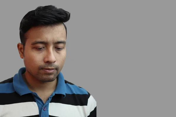 Indonesian guy looking sad with eyes down in depressed mood in grey background with copy space for text.Sad mood concept — 스톡 사진