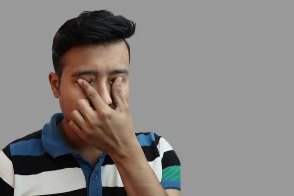 Индонезийский парень плачет в подавленном настроении с пальцами на обоих глазах на сером фоне с копировальным пространством для концепции text.Sad настроение — стоковое фото