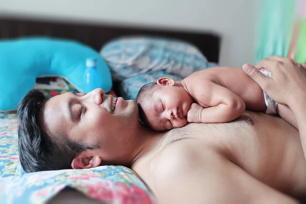 Ein Baby mit nacktem Körper, das friedlich auf dem Körper seines Vaters schläft. Vaterschaftskonzept Elternschaft Foto Stockbild
