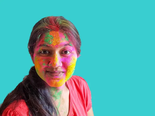 Portret van een jonge dame met holi kleuren lachend naar de camera met geïsoleerde vaste cyaan achtergrond — Stockfoto