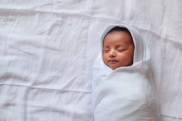Egy egyhónapos baba alszik, és pólyázott fehér ruhába feküdt fehér ruha háttér — Stock Fotó