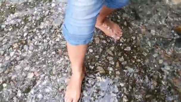 Feet of a lady wearing jeans dipped and splashing water in slow motion — Stock Video