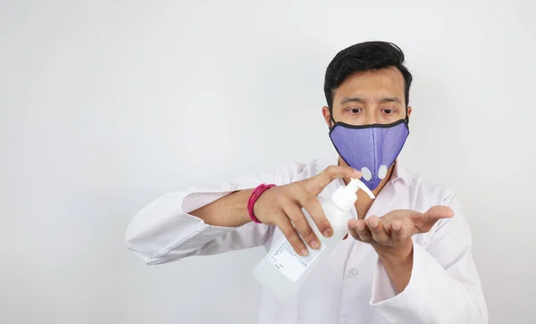 Un medico maschio in maschera e mantello bianco che dimostra l'uso di disinfettante per le mani. Protocollo lavaggio mani — Foto Stock