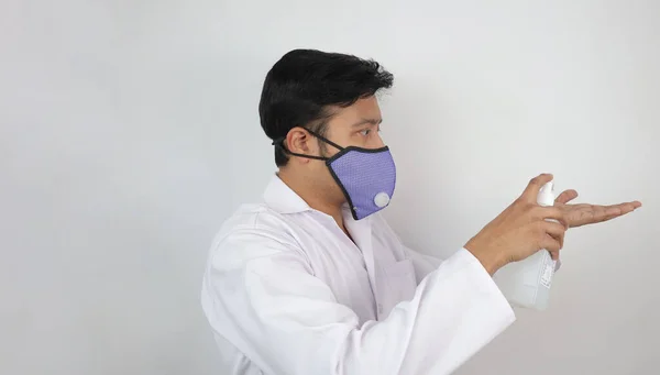 En manlig läkare i mask och vit rock som visar användning av handdesinfektionsmedel. Handtvättningsprotokoll — Stockfoto