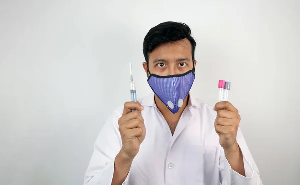 A medical professional in white coat and protective mask holding vials and syringe in hand — Stock Photo, Image