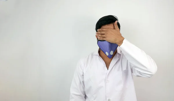 En manlig läkare i vit rock och mask i vit bakgrund. stressad läkare dölja identitet. konceptbild för virusinfektion — Stockfoto