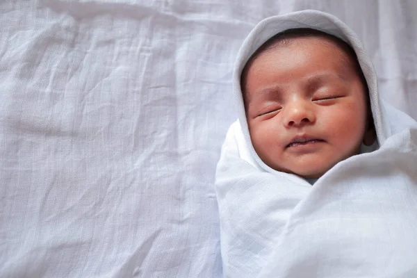 En månad gammal baby sova och lindade i vit duk som ligger i vit duk bakgrund — Stockfoto