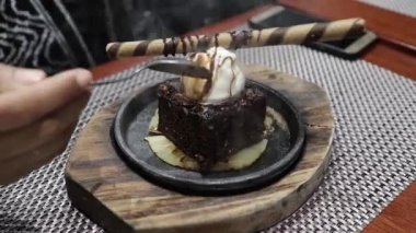 Sıcak tabaktan cızırdayan çikolatalı dondurmayı dilimliyorum.