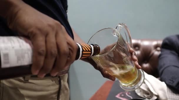 Nalévání piva do hrnku z láhve, která vytváří pěnu — Stock video