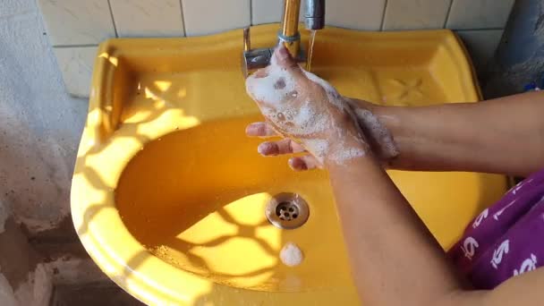 Mycie rąk mydłem w pobliżu żółtej umywalki w ciągu dnia podkreślając opuszki palców, aby zapobiec wirusowi i zakażeniu — Wideo stockowe