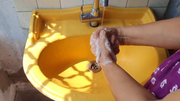 Lavage des mains avec du savon près d'un lavabo jaune pendant la journée mettant en évidence la zone du pouce pour prévenir le virus et l'infection — Video