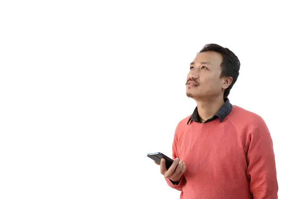 Un hombre con un teléfono móvil en la mano aislado en fondo blanco mirando un espacio de copia en blanco —  Fotos de Stock
