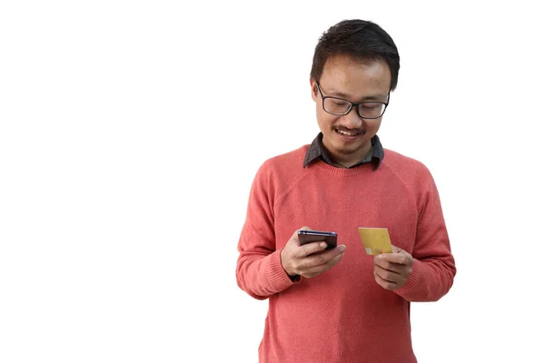 Un hombre mirando su tarjeta de crédito y teléfono inteligente. Comercio electrónico e imagen concpt de pago aislado en fondo blanco con espacio para texto —  Fotos de Stock