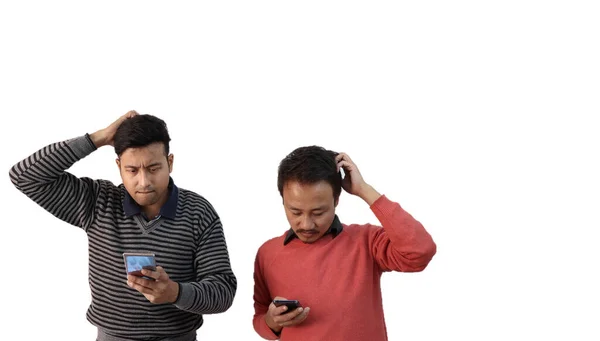 Dwóch mężczyzn o różnym pochodzeniu etnicznym patrzących na swój telefon, zdezorientowanych i drapiących głowy w białym tle z miejscem na tekst — Zdjęcie stockowe