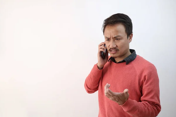 一个带着愤怒的不愉快心情在电话里交谈的男人，被白色的背景隔开，有空白处可以发短信 — 图库照片