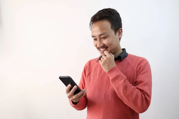Un hombre mirando su teléfono en un estado de ánimo feliz aislado en fondo blanco con espacio para el texto —  Fotos de Stock