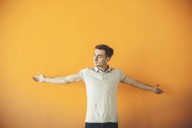 Yakışıklı çekici. Rahat kıyafet silah tutmak yakışıklı genç adam geçti ve üzerinde turuncu arka plan ayakta gülümseyen izole