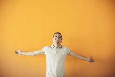 Yakışıklı çekici. Rahat kıyafet silah tutmak yakışıklı genç adam geçti ve üzerinde turuncu arka plan ayakta gülümseyen izole