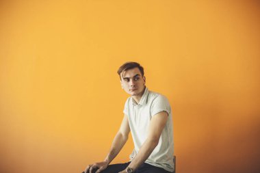 Turuncu arka planı gülümseyen yakışıklı bir genç adam portresi