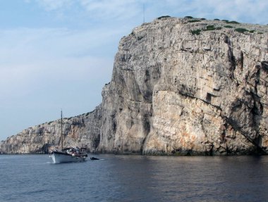 Dış Adaları'nın Hırvatistan milli doğa Park Krka ölçekler. Arka plandaki sarp kayalıklarla yelkenli tekne. Avrupa. Adriyatik Denizi Akdeniz bölgesi. Dalmaçya riviera. Sonbahar 2015.