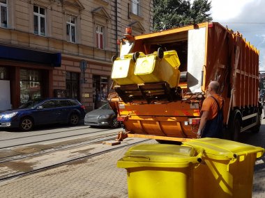 Bir kamu işçisi tarihi şehir çöp kamyonunda çöp kutuları çöp toplar. Şehir hayatı ekolojisi. Modern dünyada atık yönetimi. Prestijli ve uygun çalışma.