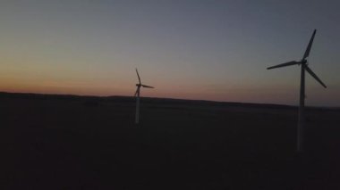 İHA 'nın günbatımında rüzgar santrali. Romantik akşam ve ekolojik olarak temiz elektriğin modern teknolojileri. Çevrenin korunması. Parlak Gelecek. Enerji çekmenin alternatif bir yolu.