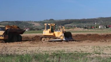 Vislock Nehri, Polonya - 2 Mayıs 2018:A damperli kamyon toprak ile yüklenir. Buldozer nehir çakıl ocağı earthland eserlerinde eşittir. Doğal kaynakların çıkarılması. Kedi tarafından üretilen bir buldozer