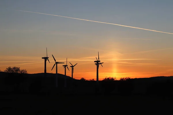 Wind power station in sunset. Romantic evening and modern technologies of ecologically clean electricity. Protection of the environment. Bright Future. An alternative way of extracting energy.