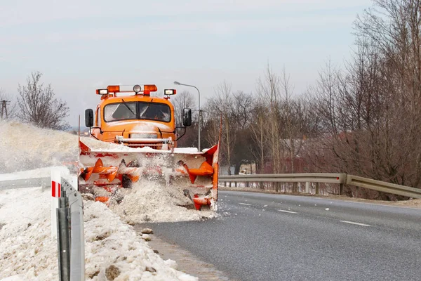 一辆有犁的大车把道路从雪中清理干净。橙色货物专用设备在冬季与元素作斗争。消除雪灾的影响。交通困难。冷冻水 — 图库照片