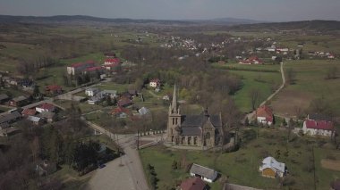 Cieklin, Poland - 4 9 2019: Panorama of a small European village with a Christian Catholic church in the center. Farms among green picturesque hills. Panorama of the Carpathian region with a drone