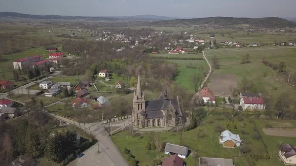 Cieklin, Polska - 4 9 2019: Panorama małej europejskiej wioski z kościołem katolickim w centrum. Gospodarstwa wśród zielonych malowniczych wzgórz. Panorama regionu Karpat z dronem — Zdjęcie stockowe