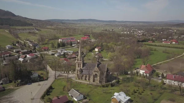 Cieklin, Poland - 4 9 2019: Panorama of a small European village with a Christian Catholic church in the center. Farms among green picturesque hills. Panorama of the Carpathian region with a drone — Stockfoto