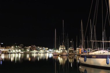 Night parking of yachts in the Croatian ACI marina of the town of Jazira. Burning lights of the evening Mediterranean port with sailing yachts and fishing boats. Twilight on the Adriatic Riviera. Calm