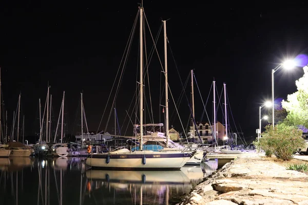 Night parking of yachts in the Croatian ACI marina of the town of Jazira. Burning lights of the evening Mediterranean port with sailing yachts and fishing boats. Twilight on the Adriatic Riviera. Calm — 스톡 사진