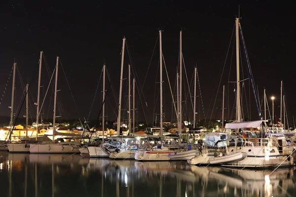 Нічне паркування яхт на хорватській асі марини в місті Джазіра. Спалювання вогнів вечора середземноморського порту з парусними яхтами і рибальськими човнами. Сутінки на Адріатичній Рив'єрі. Спокійно — стокове фото