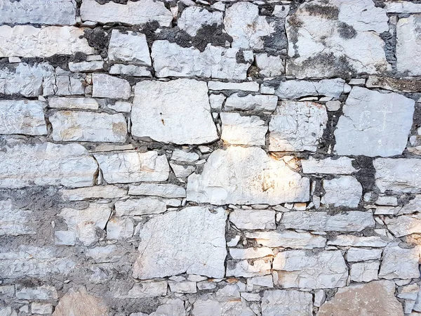 Ancient medieval stone masonry. Texture of a fragment of a wall of an old structure. A background for design and creative work. Decoration and exterior decoration of the building. Construction works — Stock Photo, Image