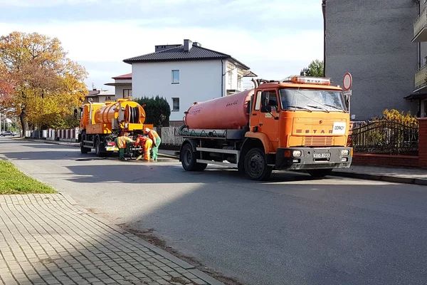 Riolering wissen met speciale technische middelen op de straten van een kleine Europese stad. Oranje auto's en gemeentelijke werknemers schoon de stad van puin en vuil. Infrastructuur — Stockfoto