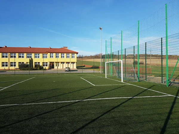 Lubno, Polen - juli 9 2018: een open stadion op de binnenplaats van een dorpsschool. Onderwijs van de jongere generatie. Sportveld voor voetbal, volleybal en basketbal. Verlichting op natuurlijke bronnen — Stockfoto