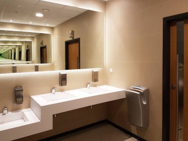 Açık bej ve beyaz renkleri banyo iç. Yuvarlak seramik lavabo. Aynalar, plastik tabak ve krom musluk bir tuvalet sonra elleri yıkamak için sabun. Karanlık karşılıklı taşlarla Tasarla