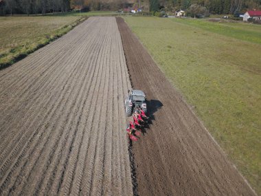Bir çiftçi bir sembol ile kırmızı bir traktör tahıl köyü alan özel bir alanda sürülmüş topraklarda sows. Mekanizasyon bahar saha çalışması. Çiftçinin günlük yaşam. Toprak işleme. Tarım