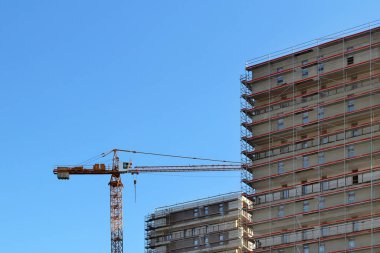 Yüksek bir çok katlı bina inşaatı. Gökdelen metal iskele ile döşenmiş. Yükseklikte tehlikeli bir iş. Modern mimari düzenleme şehir. Çevre kentleşme
