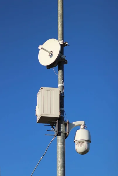 Система спостереження з помаранчевим попереджувальним світлом, розташованим на полюсі на відкритому повітрі. Загроза приватності та захист персональних даних. Відстеження безпеки на вулицях міста. людської маси — стокове фото