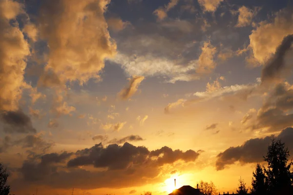 Pôr do sol sobre a aldeia. Coloração dramática do céu da noite com nuvens cumulus. Gama dourada de cores da natureza. Previsão de mudanças climáticas. Humor romântico. Sílhueta preta — Fotografia de Stock