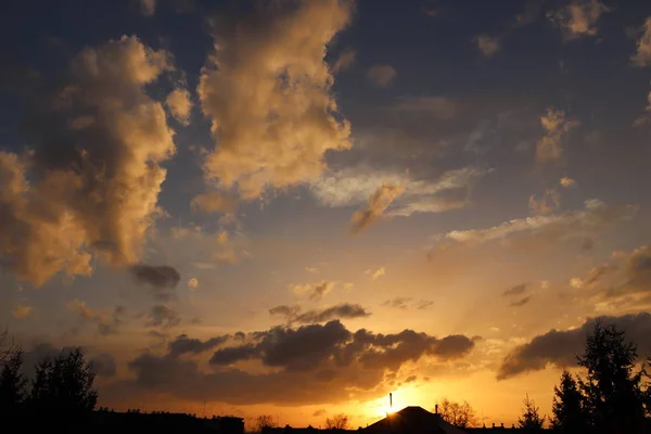 Sonnenuntergang über dem Dorf. dramatische Färbung des Abendhimmels mit Kumuluswolken. Goldene Palette von Farben der Natur. Vorhersage wechselnder Wetterbedingungen. Romantische Stimmung. schwarze Silhouette — Stockfoto