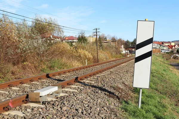 Sensor signaling the passage of the train on the railway track to activate the alarm at a road crossing. Mound of coarse gravel with rails and sleepers for transporting locomotive and wagons — Stock Photo, Image