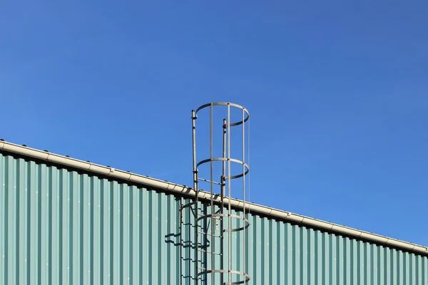 Metal fire escape on the roof of an industrial building against the blue sky. Safety of the work of people. Evacuation during stoichiyskogo disaster. Service passage — Stock Photo, Image