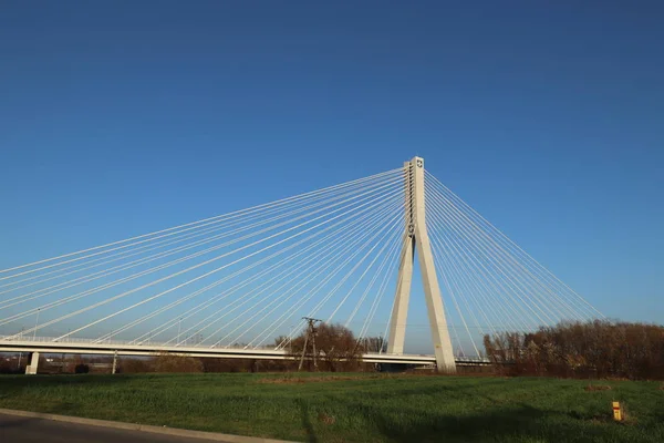 Rzeszow, Polsko - 9 9 2018: Suspendovaný silniční most přes řeku Wislok. Technologická struktura kovové konstrukce. Moderní architektura. Bílý kříž na modrém pozadí je symbolem města — Stock fotografie